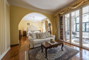 Un salon avec un canapé, une table basse et une grande fenêtre avec des rideaux.