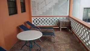A balcony with two lounge chairs, a small round table, and a decorative white partition. - Fabulous Lab 1 Bedroom (Laborie)