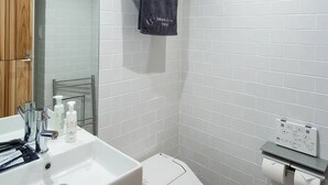 Un baño moderno con un lavamanos blanco, un inodoro y un perchero para toallas.