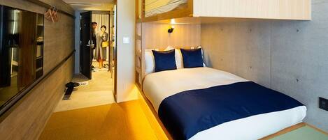 A compact hotel room with a bunk bed, a small kitchenette, and a bathroom visible through an open door.