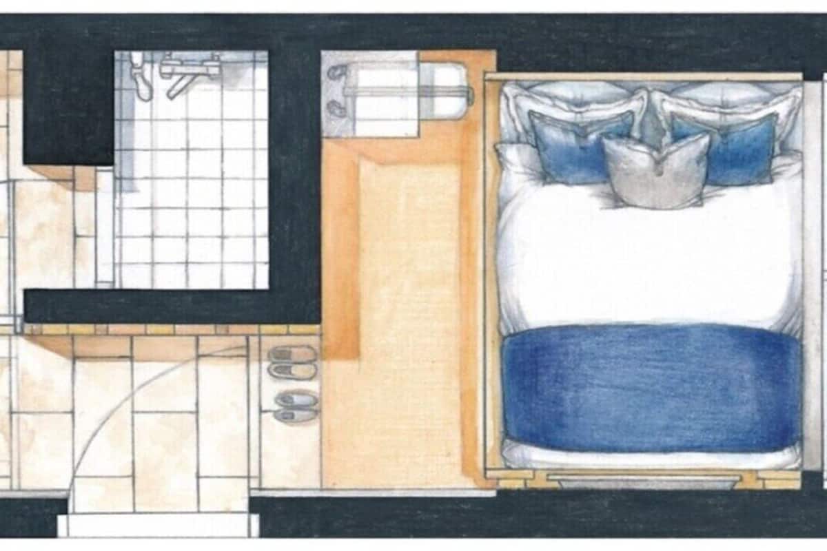 Plano de un cuarto de hotel con cama, baño, una pequeña zona de estar y una kitchenette.