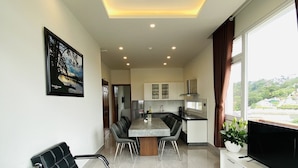 Una sala de estar moderna con comedor, cocina y televisor sobre un mueble.