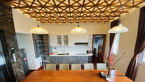 Una cocina moderna con una isla central, armarios blancos y estructura de techo de madera.