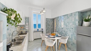A modern kitchen with a dining area, a view of the sea, and a refrigerator. - Seaview Home on the beach & amazing views terrace (Sorrento)