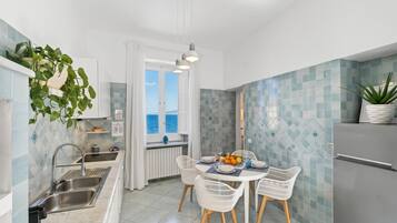 A modern kitchen with a dining area, a view of the sea, and a refrigerator.