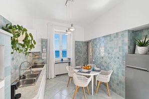 A modern kitchen with a dining area, a view of the sea, and a refrigerator. - Seaview Home on the beach & amazing views terrace (Sorrento)