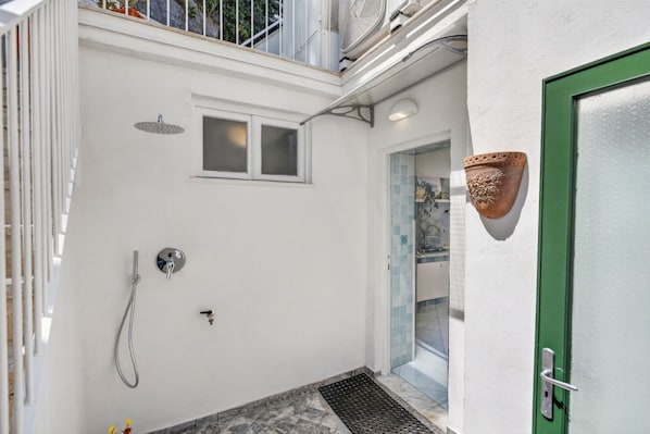 A compact bathroom with a shower, a small window, and a green door.