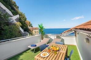 A balcony with a table set for two, a plate of food, and a fruit bowl. - Seaview Home on the beach & amazing views terrace (Sorrento)
