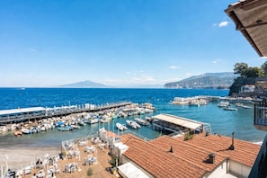 Un port de plaisance situé sur la côte, avec des bateaux amarrés, une jetée qui s’avance dans l’eau et un bâtiment doté d’un toit en tuiles.