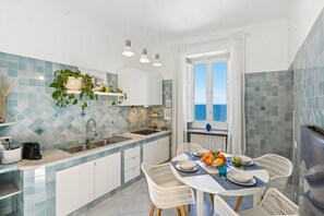 A kitchen with a dining area, a view of the sea, and a window with curtains. - Seaview Home on the beach & amazing views terrace (Sorrento)