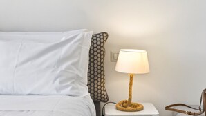 A neatly made bed with white bedding, a patterned pillow, a round table lamp with a rope base, and a brown leather bag on the side. - Seaview Home on the beach & amazing views terrace (Sorrento)
