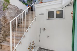 A staircase leading to a room with a shower and a window.