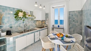 Una cocina con comedor, vista al mar y una ventana con cortinas.