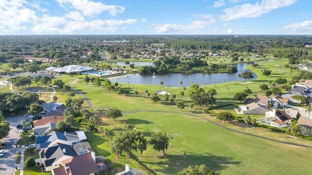 Ein Golfplatz mit Teich, umgeben von Wohnhäusern und Grünflächen.