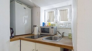 A compact kitchen with a refrigerator, microwave, toaster, and sink.