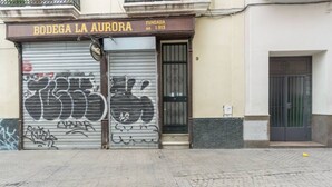 A closed storefront with graffiti on the shutter and a sign reading "BODEGA LA AURORA".