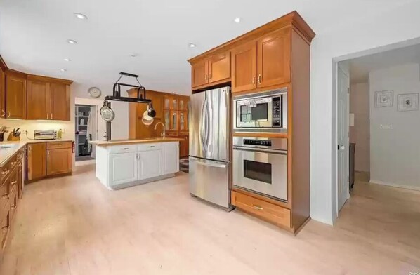 Kitchen features a central island with a sink, double oven, and microwave.