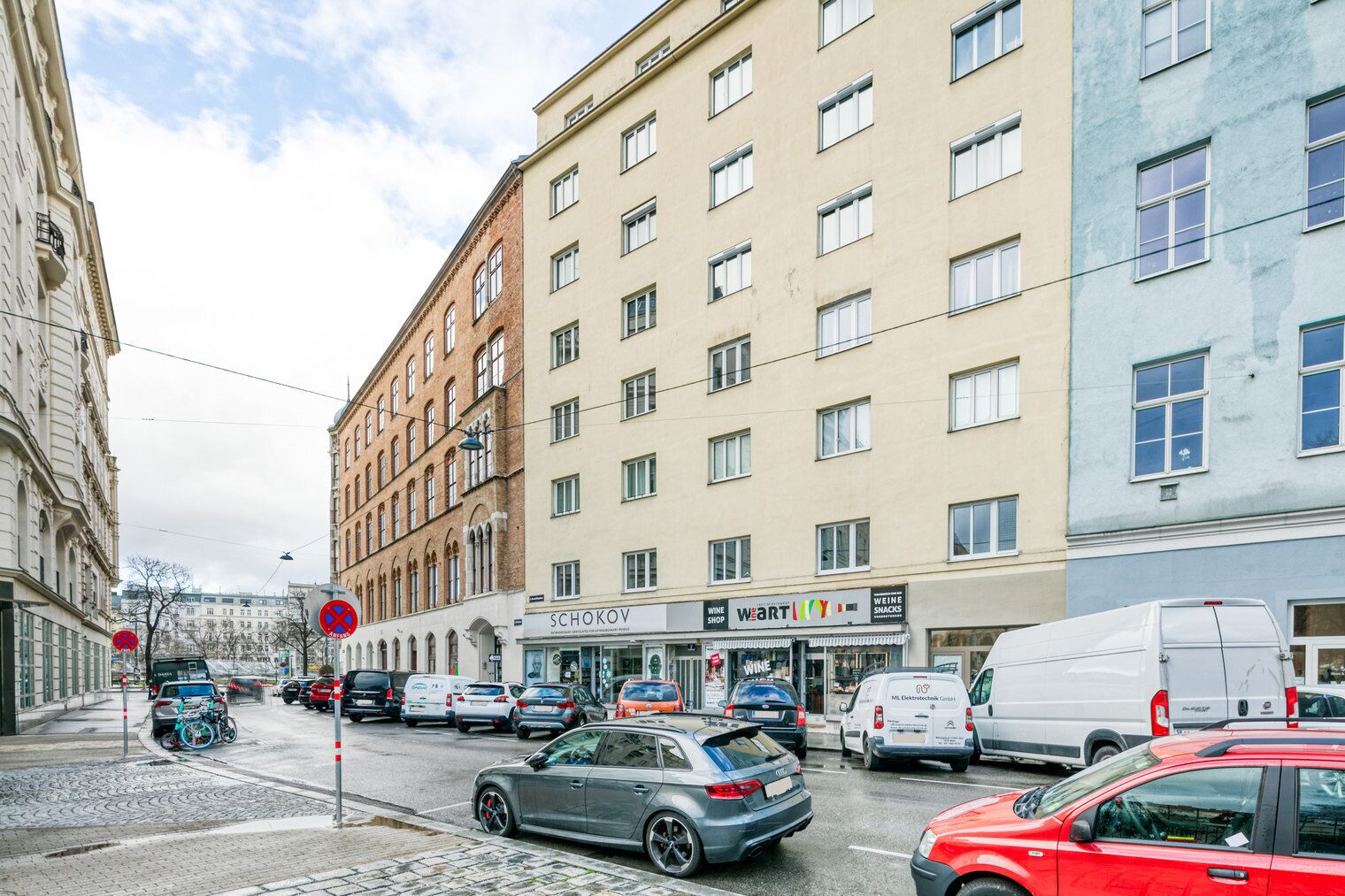 Une rue avec des voitures, un vélo et des immeubles abritant des boutiques.