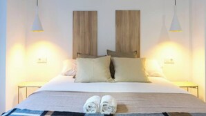 Una cama bien hecha con un edredón a cuadros, dos almohadas y toallas enrolladas sobre la cama.