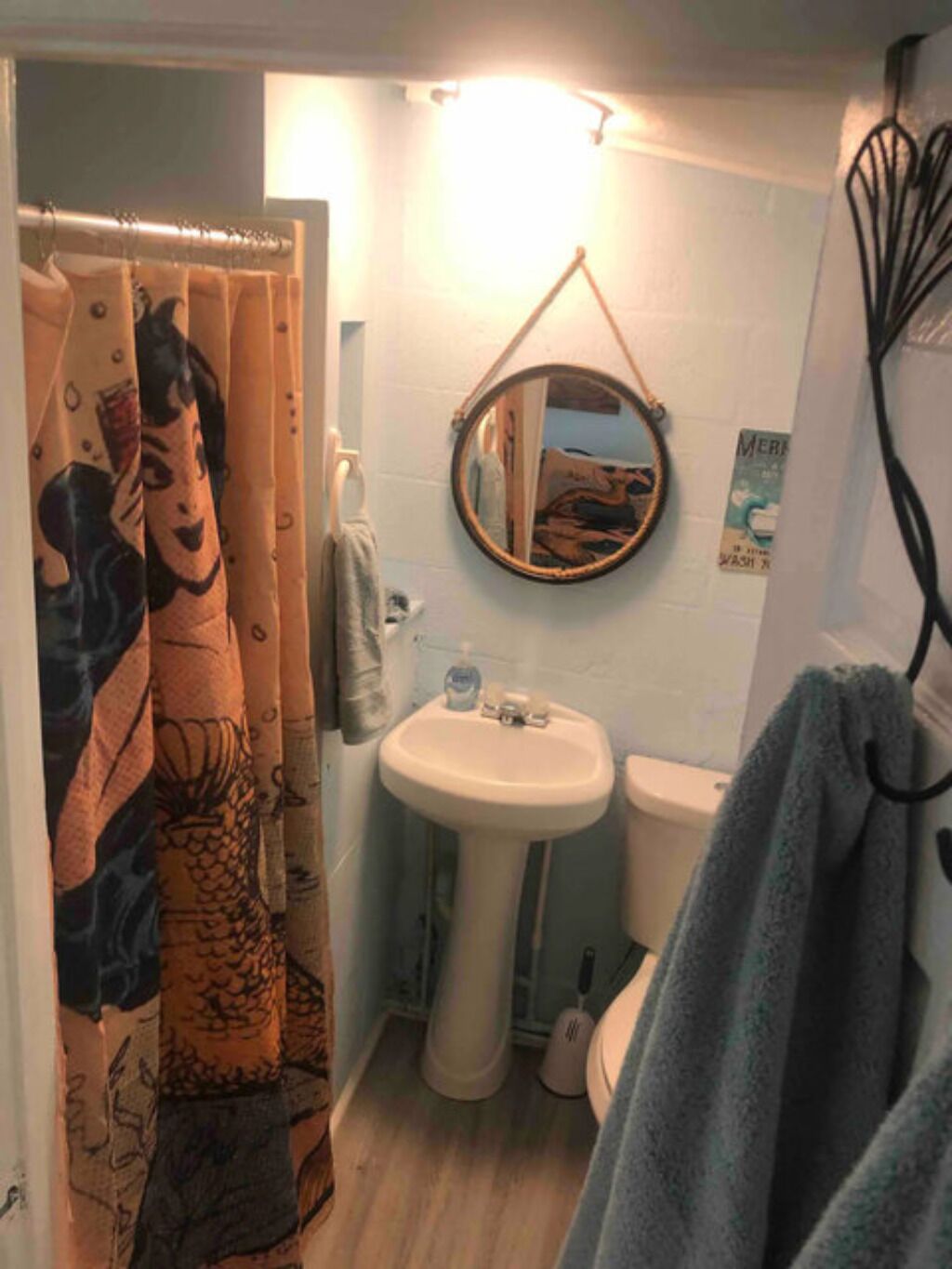 Ein Badezimmer mit Duschvorhang, Becken, Toilette und Spiegel.