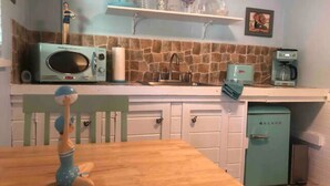 A kitchen with a microwave, coffee maker, and a vintage refrigerator.