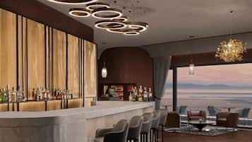 Un área de bar moderna con una barra larga, varios taburetes y vistas al océano.