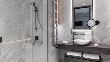 A modern bathroom with a glass-enclosed shower, a white sink, and a mirror with a round frame.