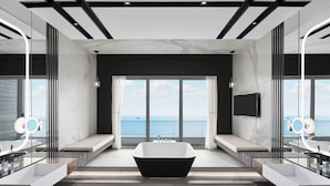 Un baño moderno con una bañera independiente, ventanas amplias y vista al mar.