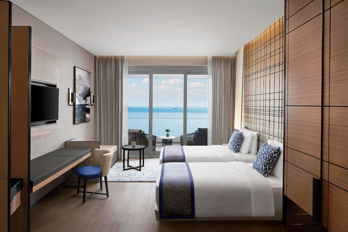 Una habitación de hotel con un ventanal grande, una cama, un escritorio y un televisor.