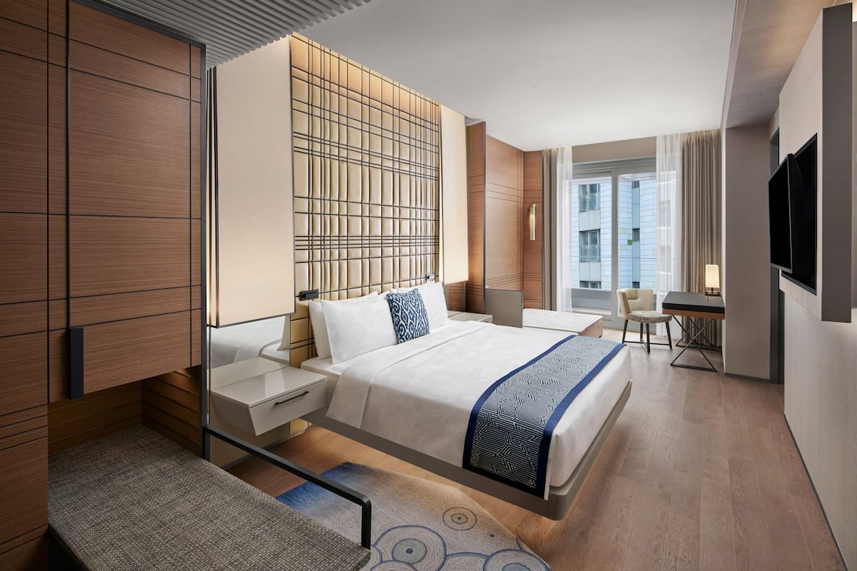 Una habitación de hotel moderna con una cama grande, mesitas de noche, un escritorio y un televisor.