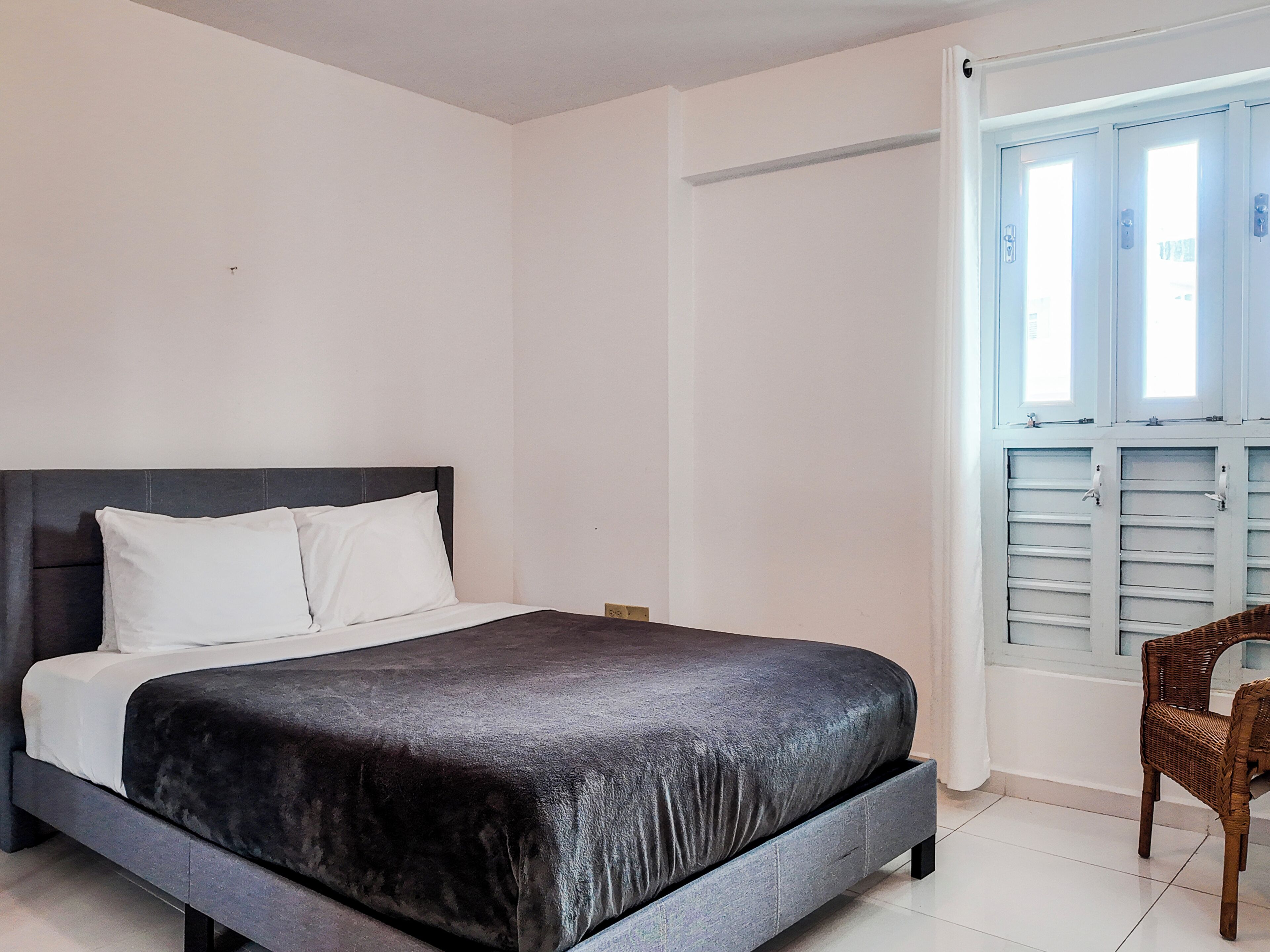 Ein Schlafzimmer mit einem Bett, einem Sessel und einem Fenster mit Rollläden.
