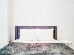 Un lit avec une tête de lit, un oreiller blanc et une couvre-lit à motifs.