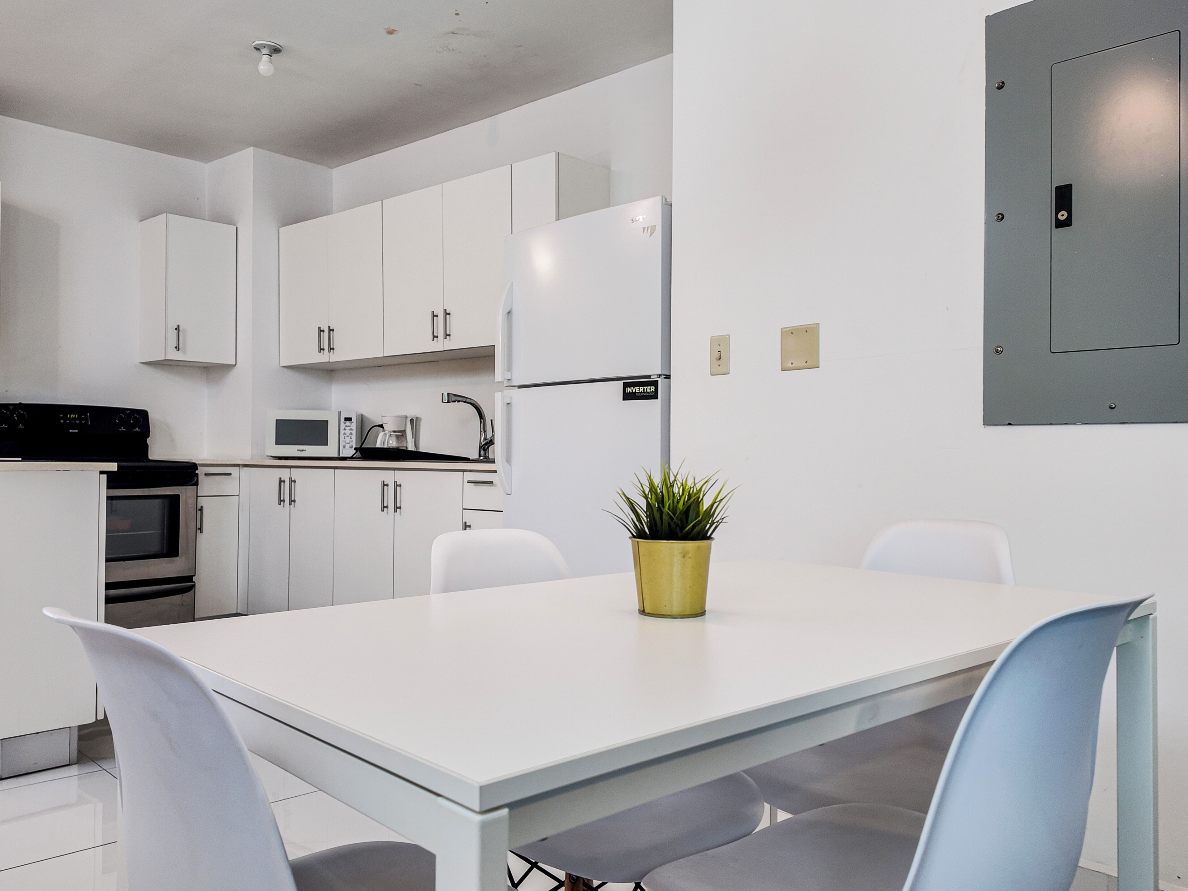 A modern kitchen with white cabinets, a stainless steel oven, a microwave, and a refrigerator.