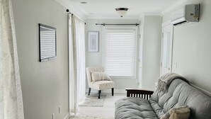 Una sala de estar con un sofá gris, un sillón estampado, una mesa de centro de mármol y una alfombra mullida.