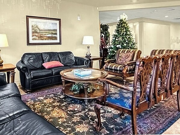 A living room with a black leather sofa, a wooden coffee table, and a patterned rug. - Orlando Golf Gated Community, Pools, Hot tub, Tennis, Golf, Fitness, Playground (Orlando)