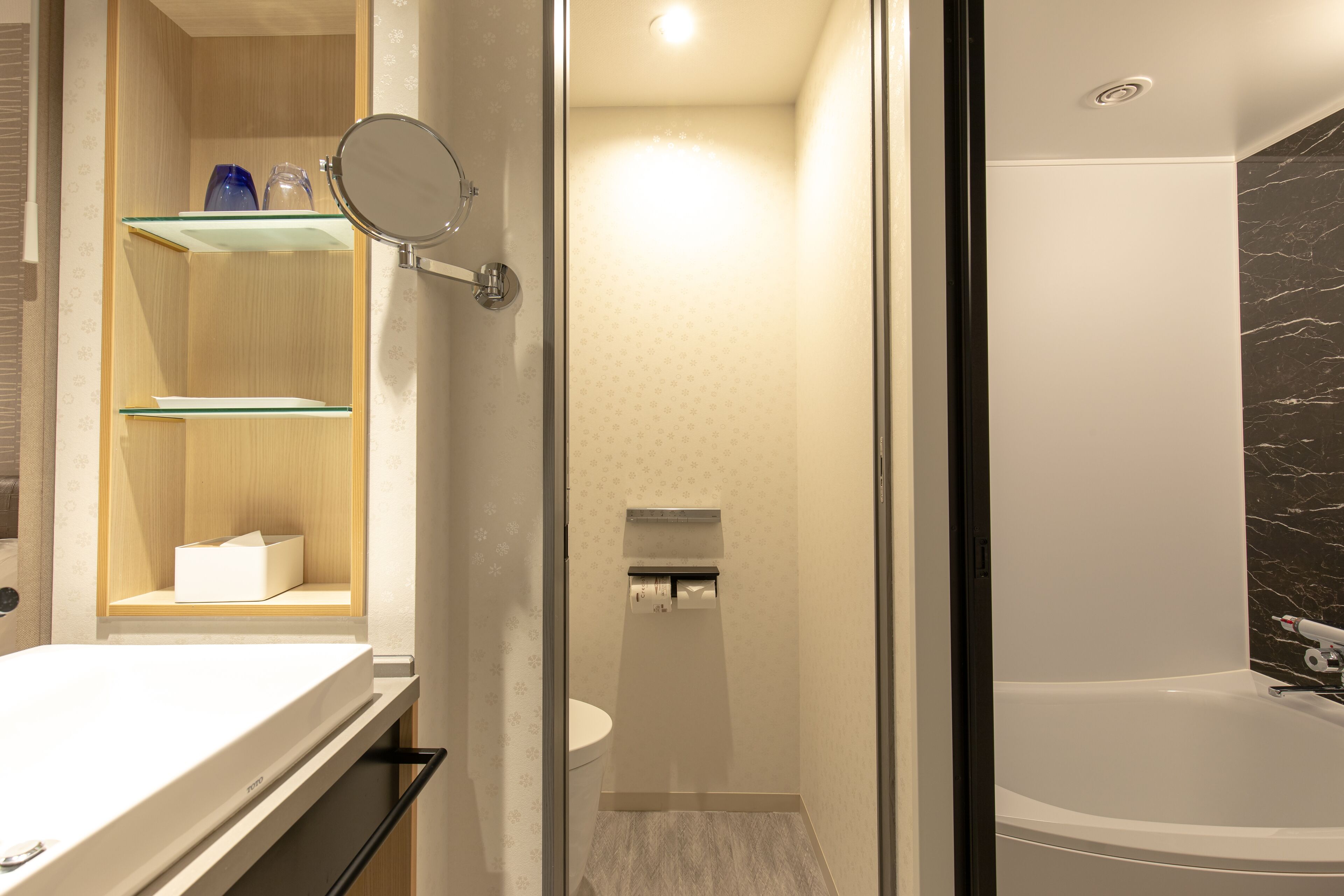 A modern bathroom with a glass shower enclosure, a built-in toilet, and a vanity with a mirror.
