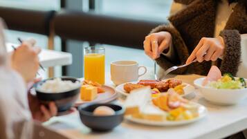 A dining table with breakfast items including a bowl of cereal, a glass of orange juice, a cup of coffee, and plates with food.