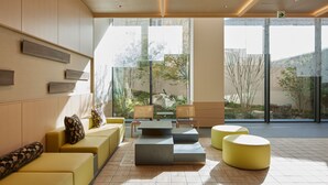 A modern lobby with a seating area, large windows, and a view of a garden. - Montblanc Hotel RAFFINE NAGOYA EKIMAE (Nagoya)
