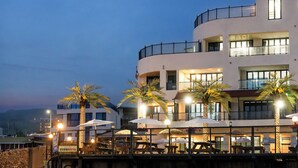 A multi-story hotel with outdoor seating, palm trees, and a view of the sea. - Gyeongju Neulsiwon Pension (Gyeongju)