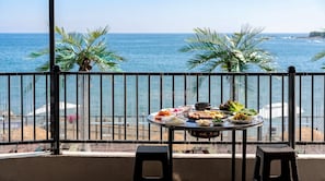 Ein Balkon mit Esstisch, der auf das Meer blickt.
