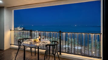 Un balcón con una mesa dispuesta para dos, con vistas a la costa de noche.