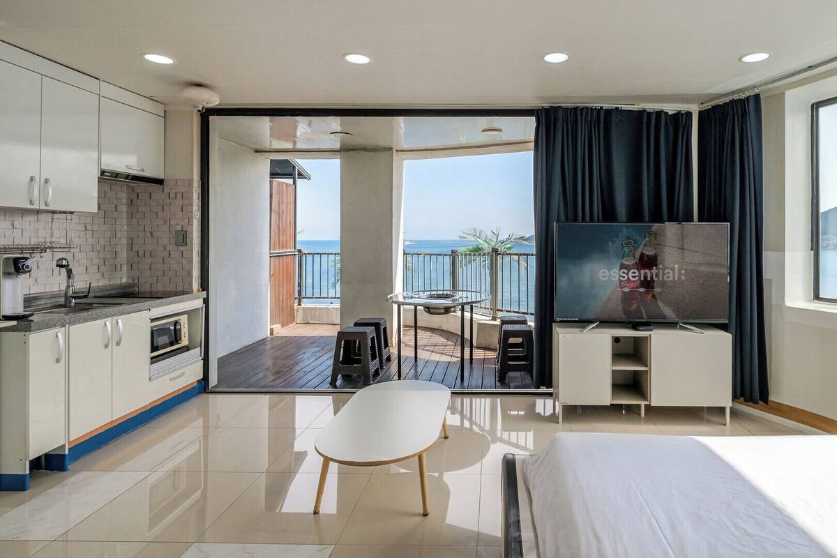A hotel room with a balcony, a dining area, a TV, and a bed.