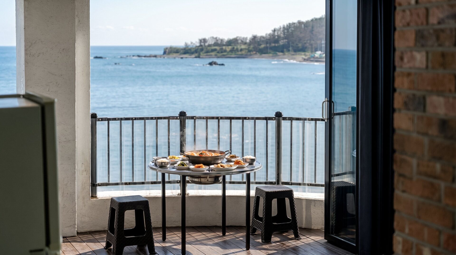 Een balkon met een eettafel, met uitzicht op een wateroppervlak en een verre kustlijn.