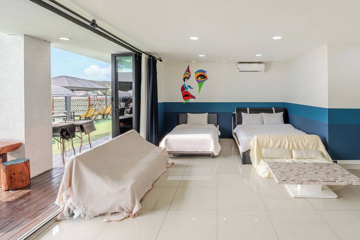 A hotel room with two beds, a large window, and a view of the outdoors.