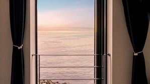 A window with a view of the sea, curtains tied back, and a metal railing. - Gyeongju Neulsiwon Pension (Gyeongju)