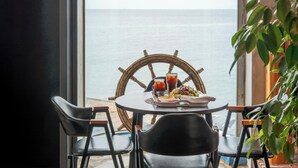 A table with chairs, a ship's wheel, and a meal by a window overlooking the sea. - Gyeongju Neulsiwon Pension (Gyeongju)