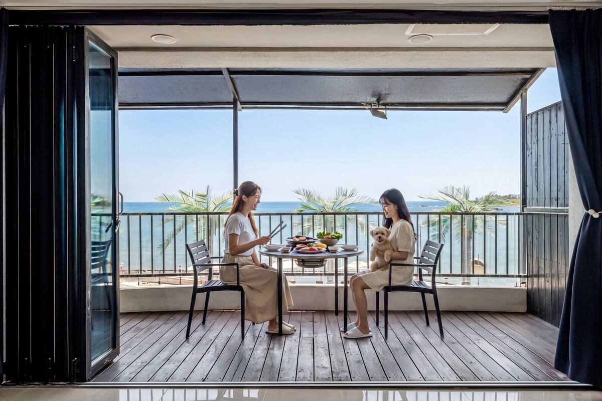 A balcony with a table set for two, overlooking a body of water.