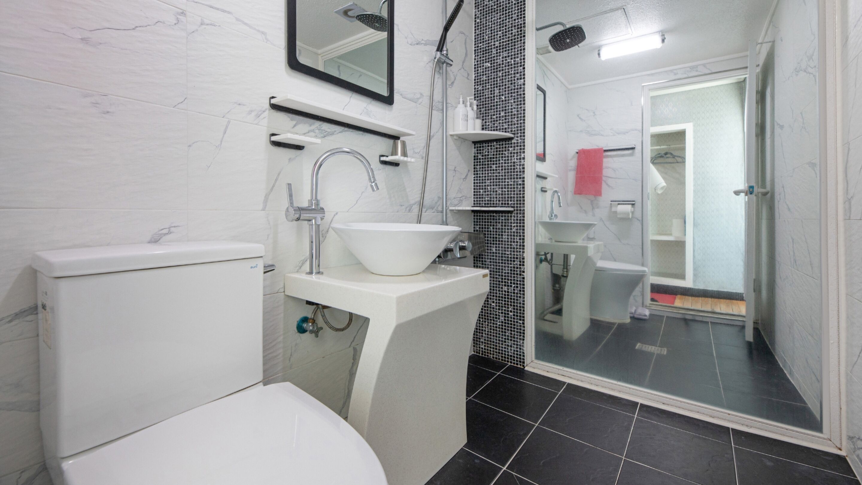 A modern bathroom with a toilet, a sink with a vessel basin, a shower area, and a glass-enclosed shower stall.
