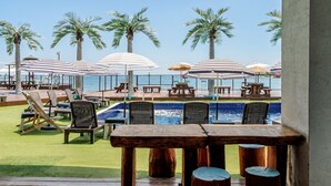 A poolside area with lounge chairs, umbrellas, and a view of the ocean. - Gyeongju Neulsiwon Pension (Gyeongju)