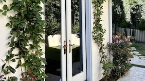 Una casa moderna con puerta de cristal, rodeada de abundante vegetación y un jardín cuidado.